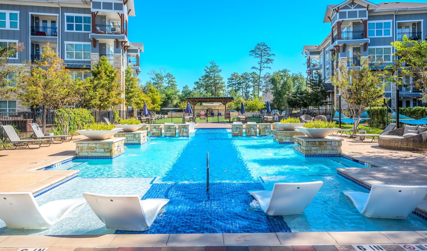 Large sparkling blue pool with a large deck and lounge chairs 